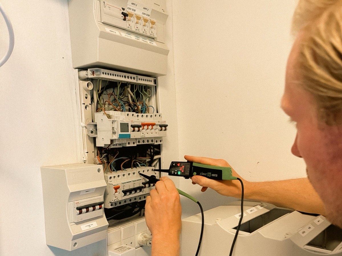 Elektriker fra Hørlykke EL måler på fejlstrømsafbryderen i en eltavle med spændingstester